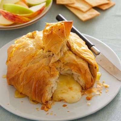 baked bread with brie oozing out on a plate with a knife on the side