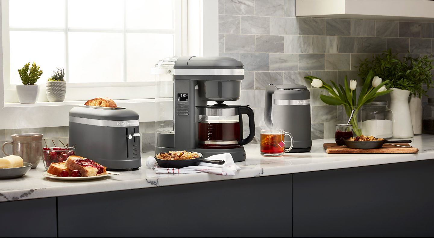 Coffee maker on countertop surrounded by fresh pastries