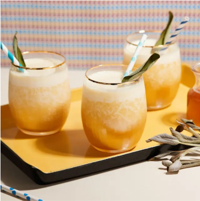 Pineapple cocktails with straws and fresh sage garnishes