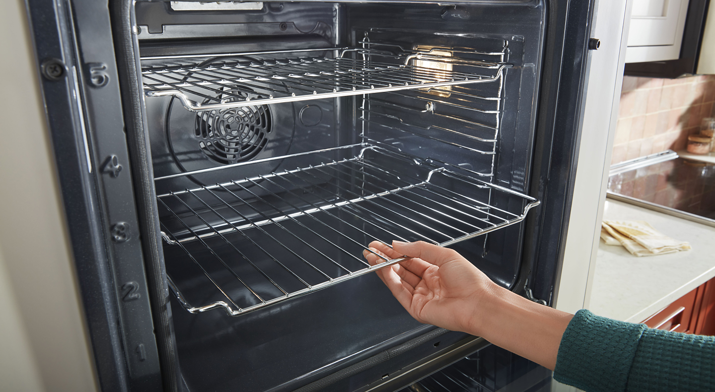 Person adjusting the racks inside an oven