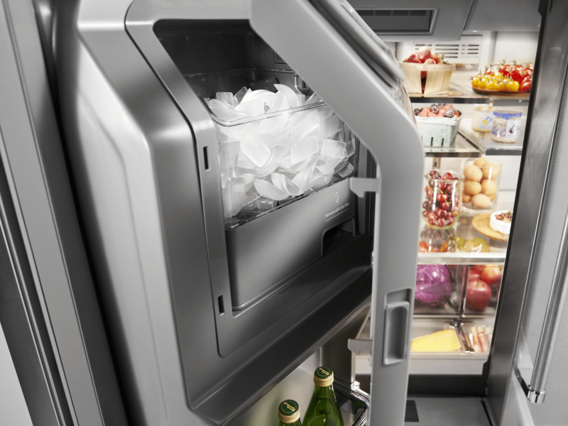 An ice dispenser in a KitchenAid® refrigerator.