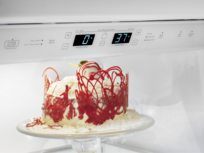 A red and white cake in a refrigerator.