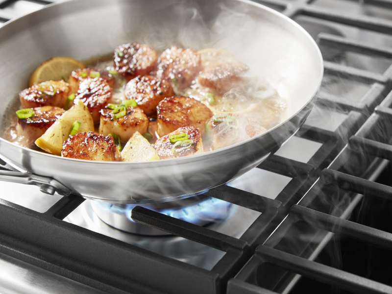 Scallops cooking on a gas cooktop