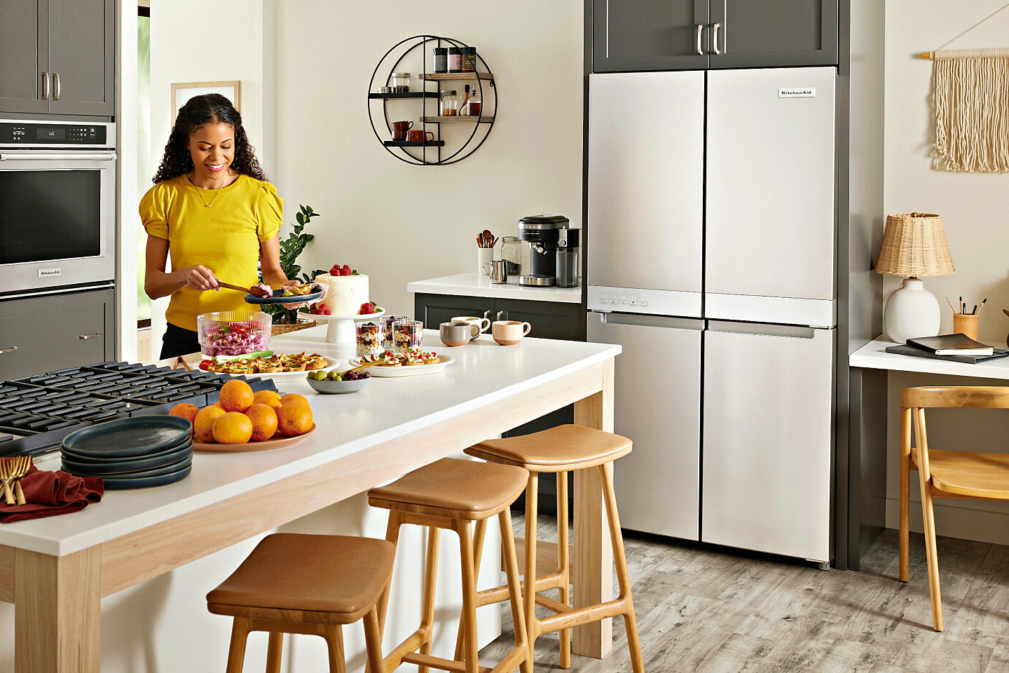 Person in a bright kitchen with a KitchenAid® 4-door refrigerator