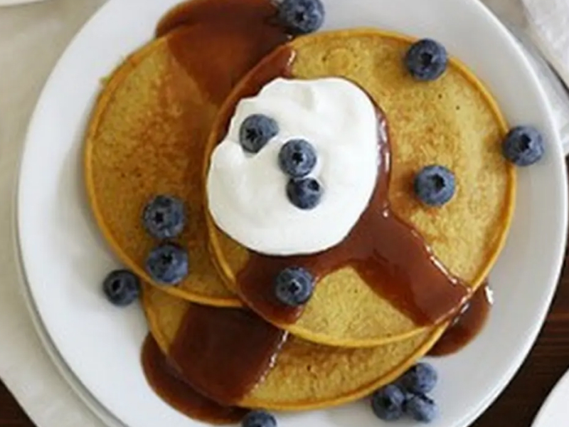 Plate of pumpkin pancakes with syrup, cool whip and blueberries on top