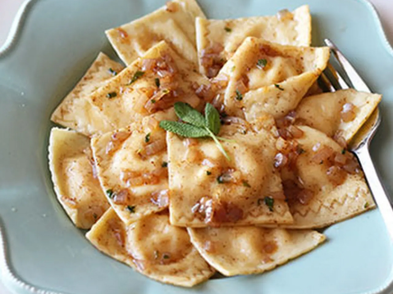 Pumpkin ravioli with browned butter sauce in a pale blue bowl