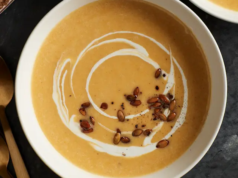 Bowl of pumpkin soup garnished with toasted pepitas
