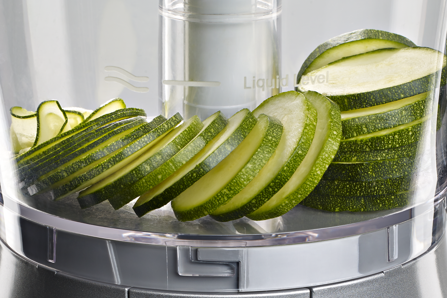 Close up image of sliced cucumbers inside a food processor work bowl