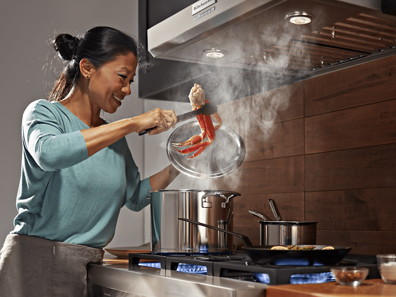 Range hood venting steam as person cooks on range below Range hood venting steam as person cooks on range below