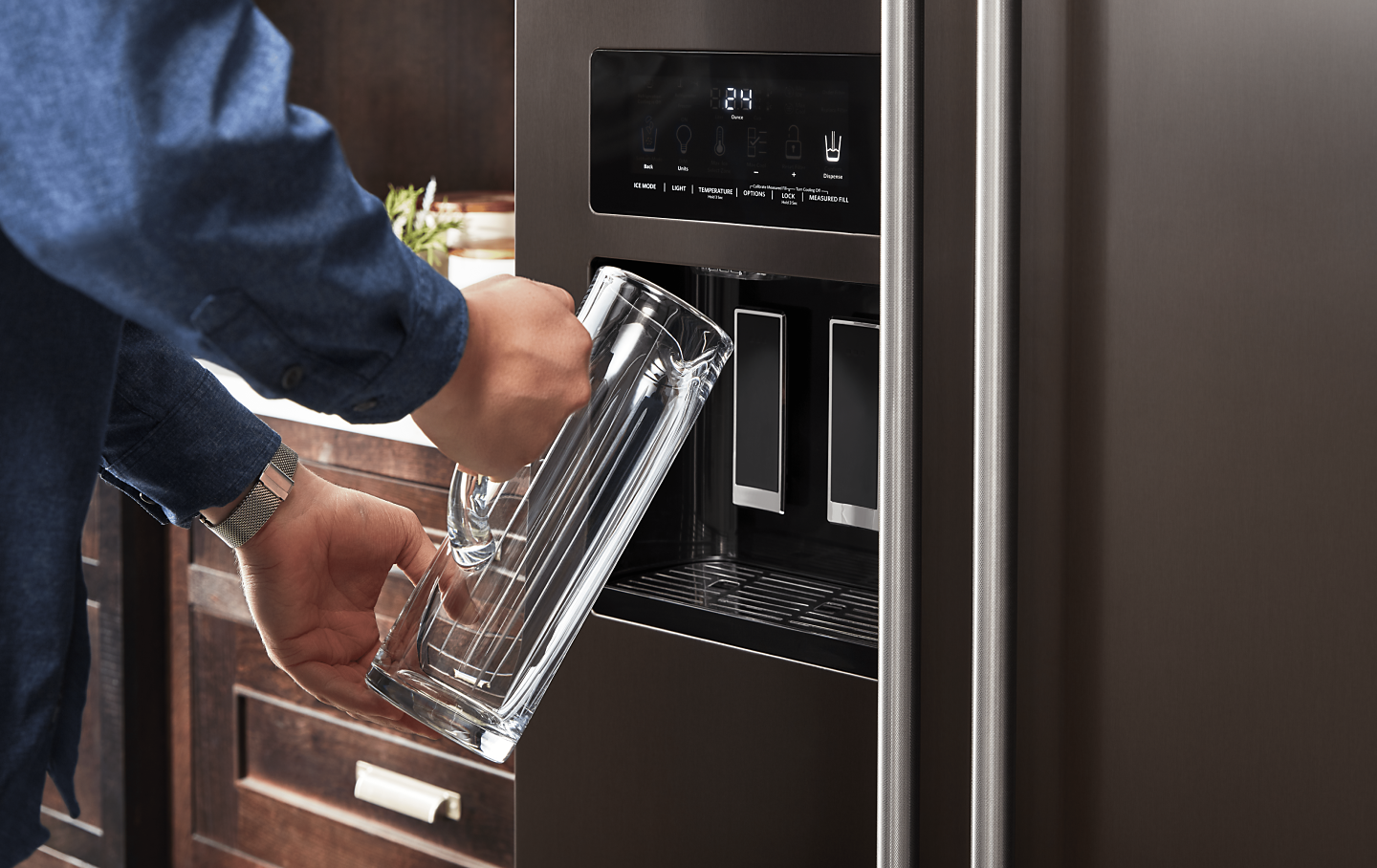 Person filling a pitcher at the refrigerator water dispenser