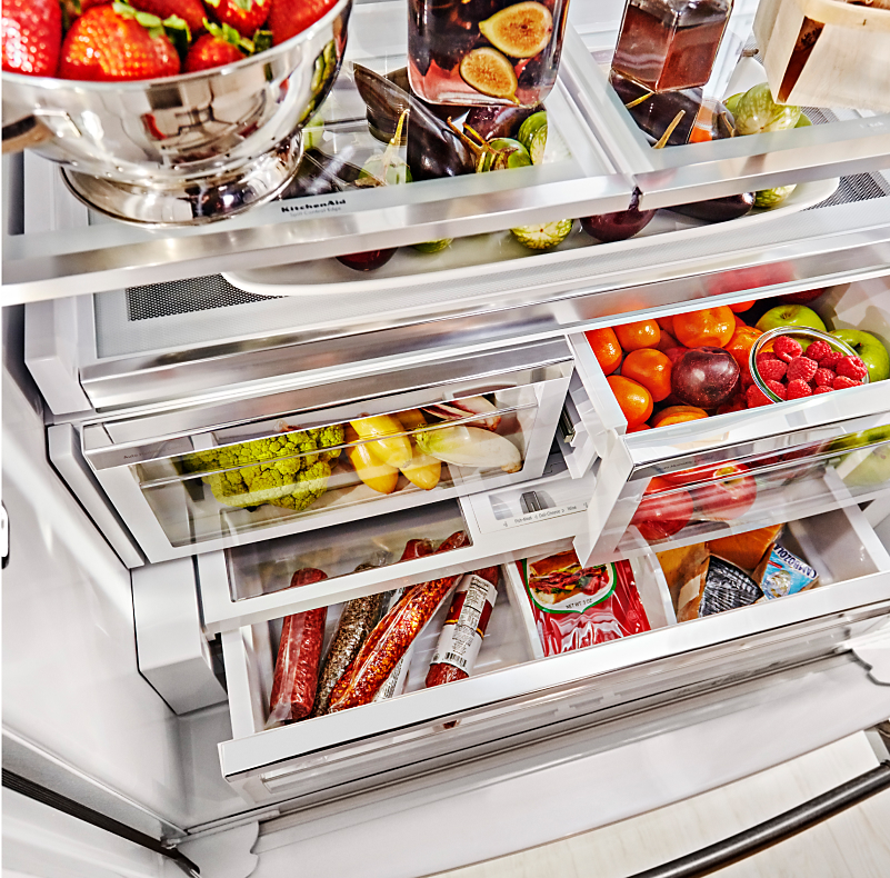 Stocked refrigerator with fruits and vegetables stored in crisper drawers.