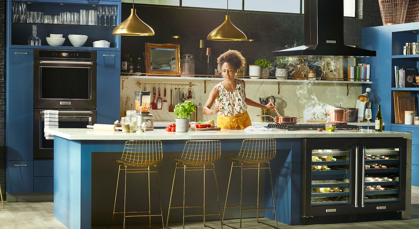 Woman preparing food in a blue kitchen with black stainless steel appliances