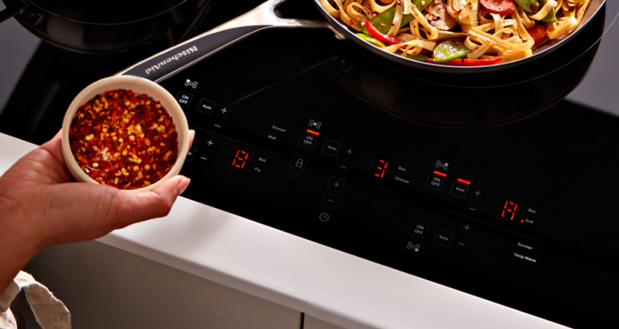 A person seasoning food at an induction cooktop.
