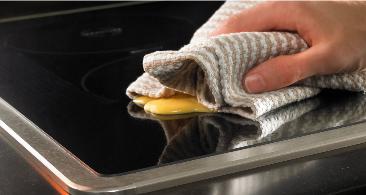 Une personne qui nettoie une table de cuisson à induction.