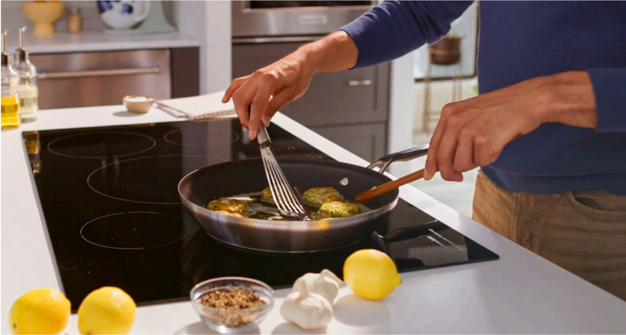 A person cooking at an induction cooktop.