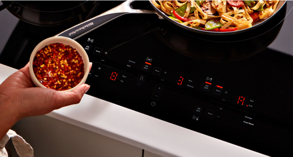 A person seasoning food at an induction cooktop.