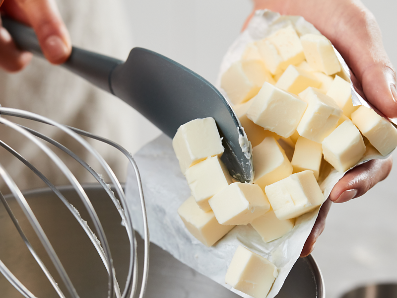 Person using spatula to put slices of butter in a bowl