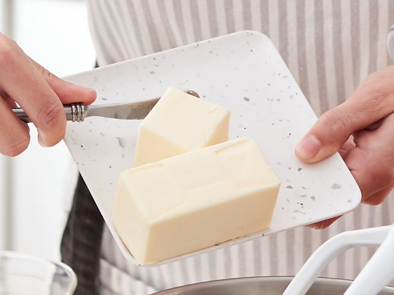 Person adding butter to a KitchenAid® stand mixer bowl