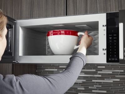 Person removing mug of water from microwave