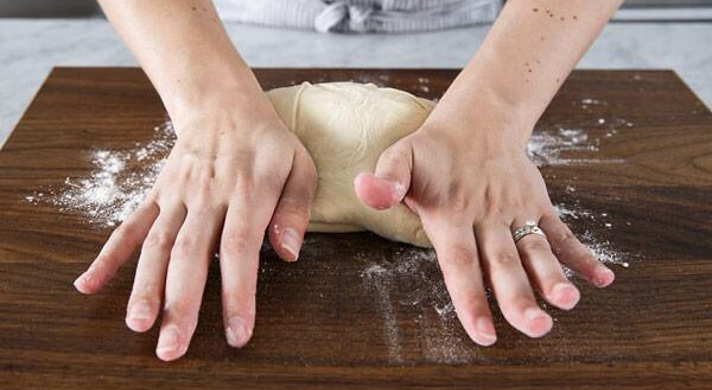 A person kneading bread by hand
