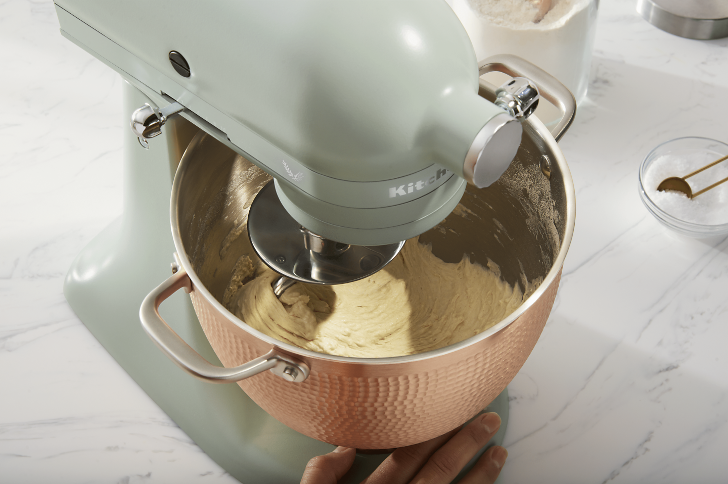 Person making pretzel dough in rose gold, textured stand mixer bowl