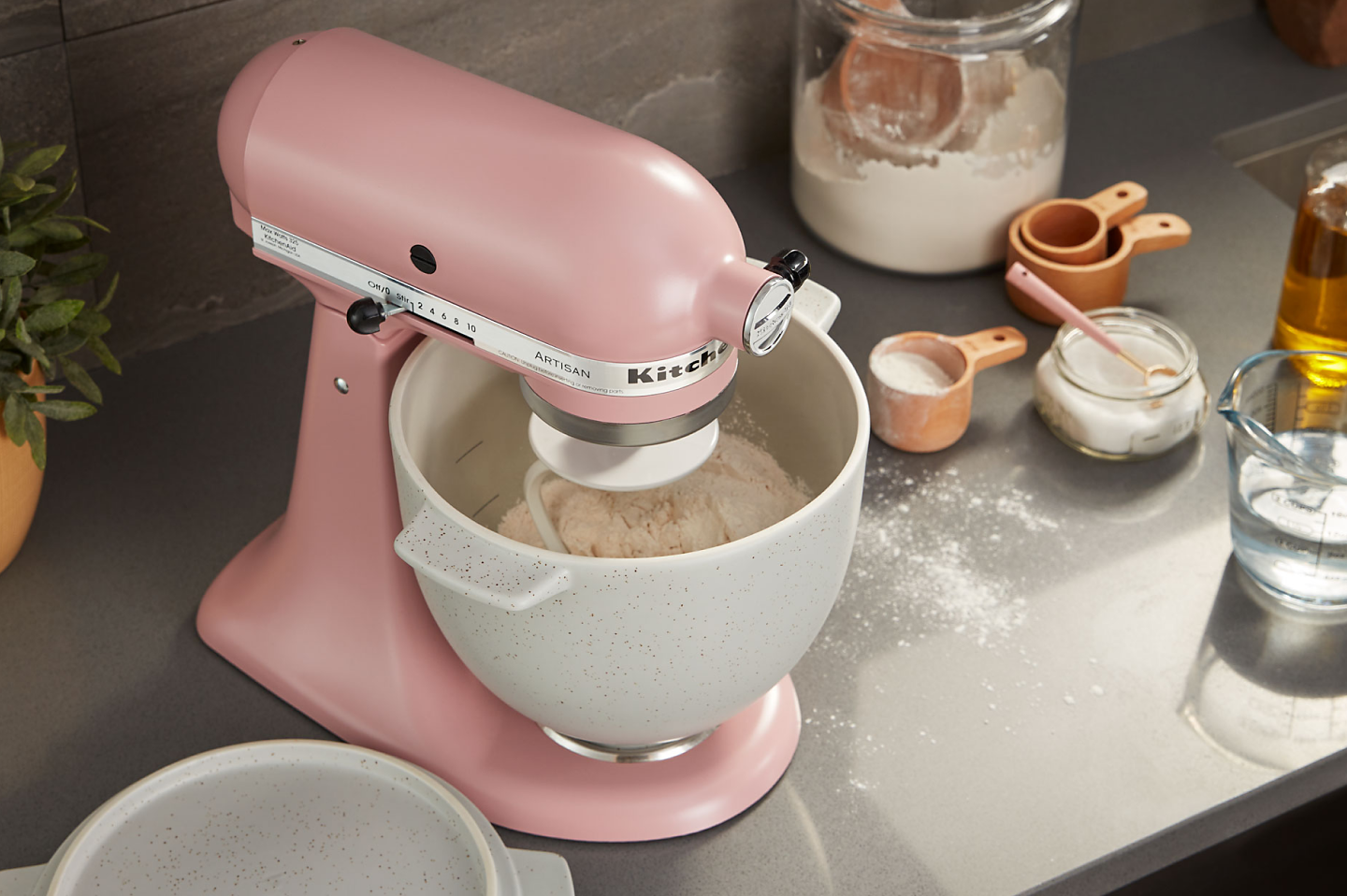 Pink stand mixer with white speckled stand mixer bowl full of flour