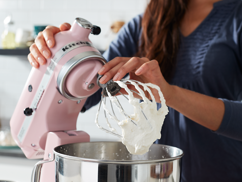 A woman using a pink KitchenAid® stand mixer to make homemade whipped cream