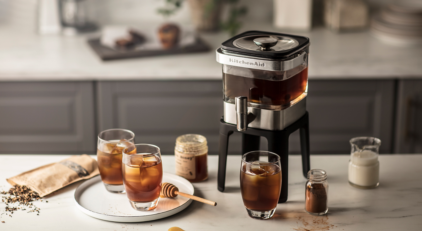 KitchenAid® cold brew coffee maker on a countertop with glasses and honey