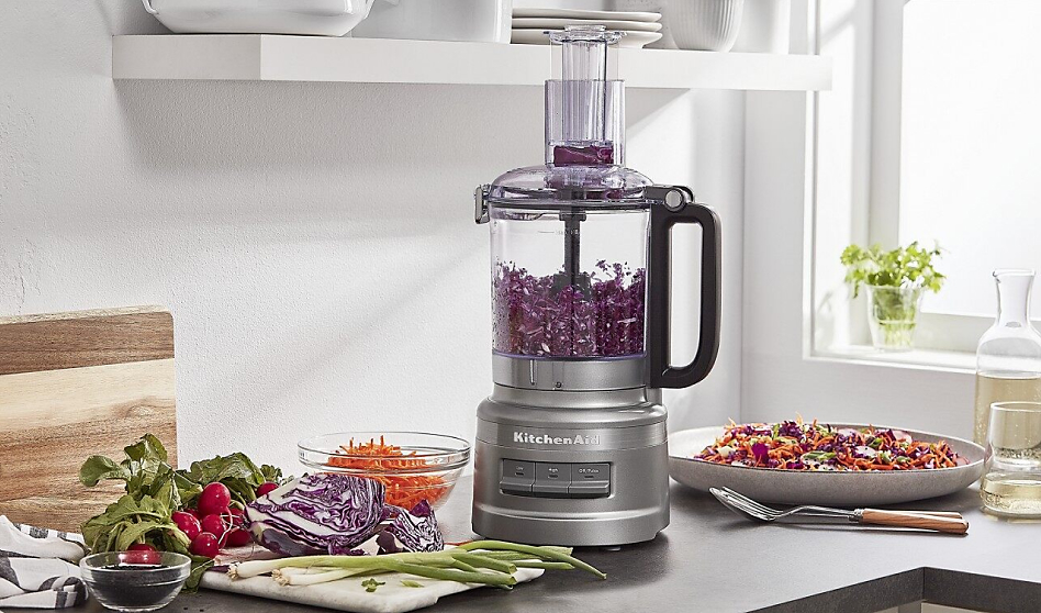 Silver food processor shredding red cabbage on counter