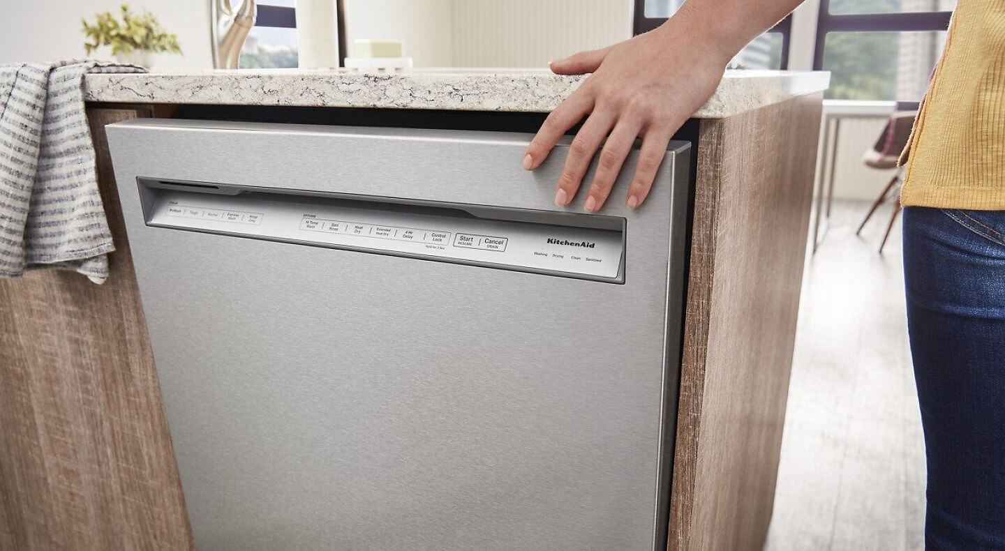 Hand touching a KitchenAid® front control dishwasher