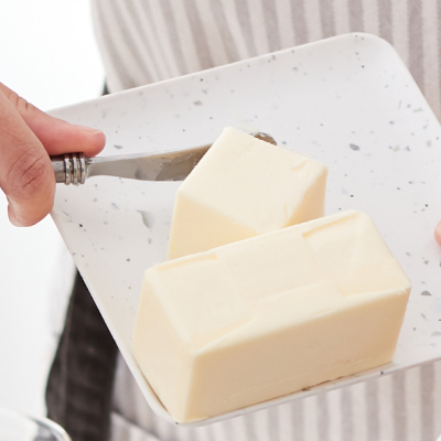 Person adjusting butter on a dish with a butter knife