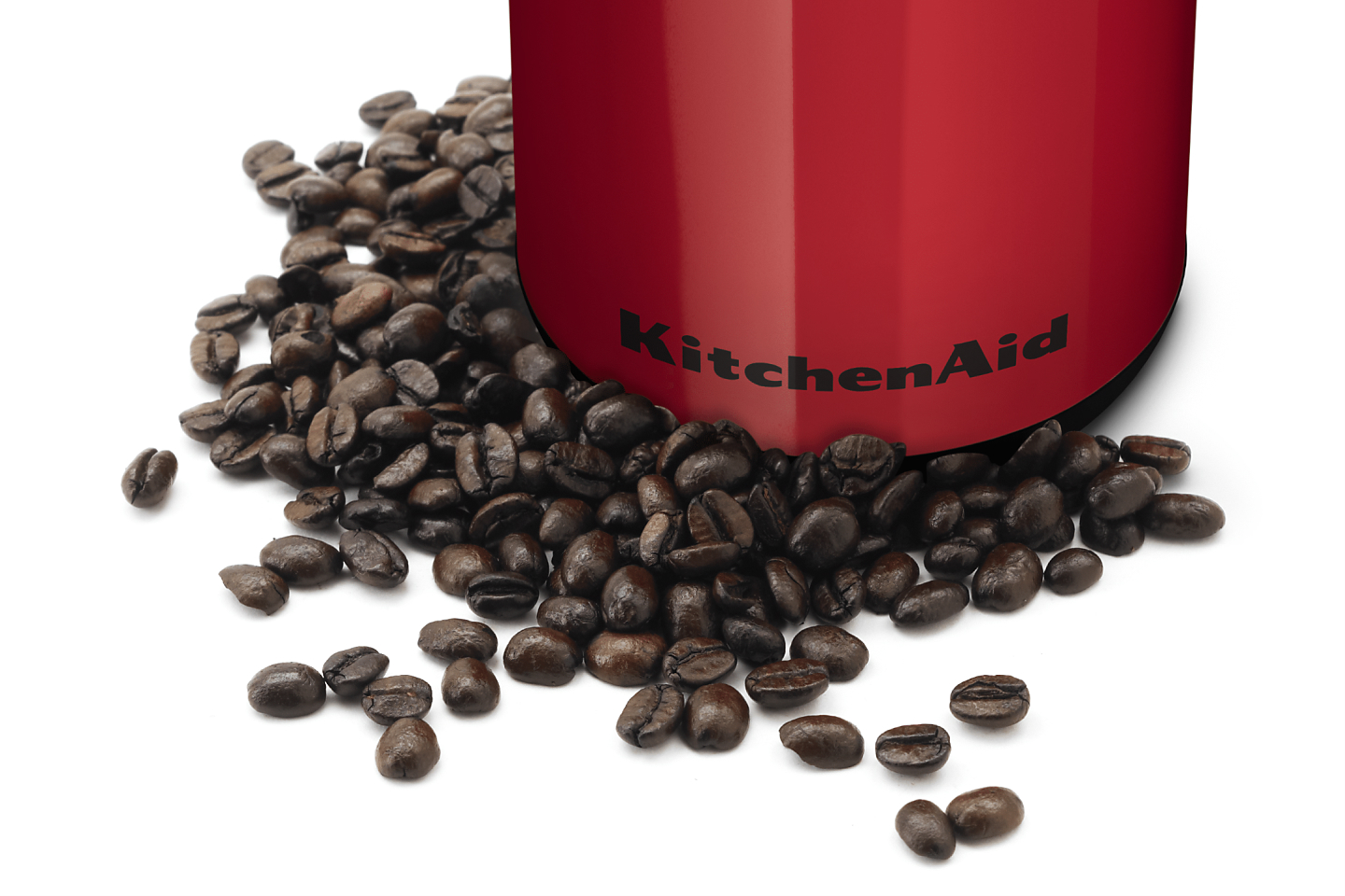 Whole coffee beans in front of a red KitchenAid® coffee grinder