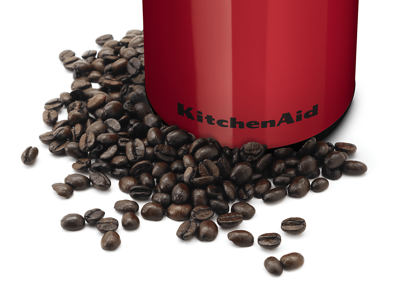 Whole coffee beans in front of a red KitchenAid® coffee grinder
