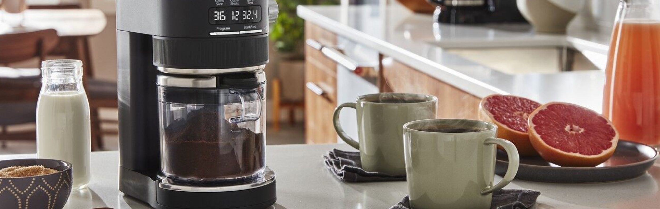 KitchenAid® Burr Coffee Grinder with coffee cups and grapefruit halves.