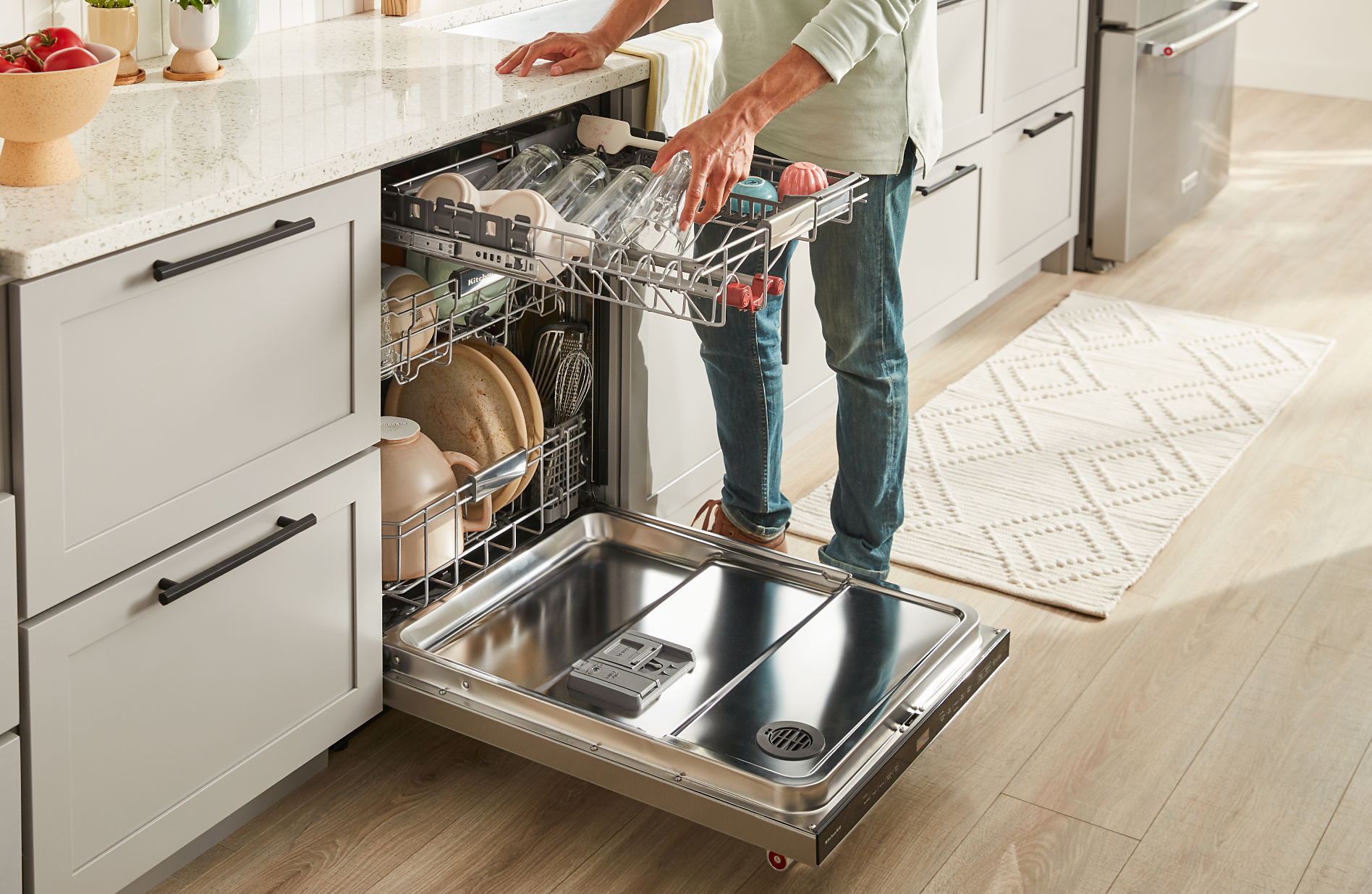 Person placing a full-sized glass in a third rack dishwasher
