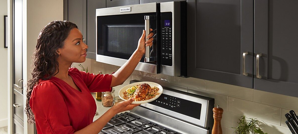 Woman placing food into an over-the-range microwave