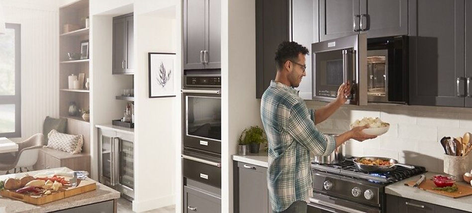 Man placing bowl in an over-the-range microwave