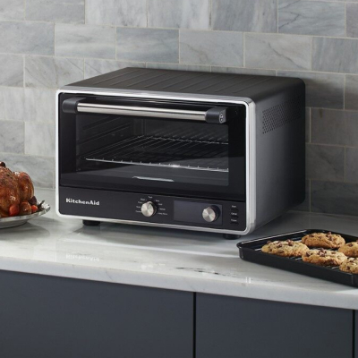 A KitchenAid® countertop oven next to baked cookies.
