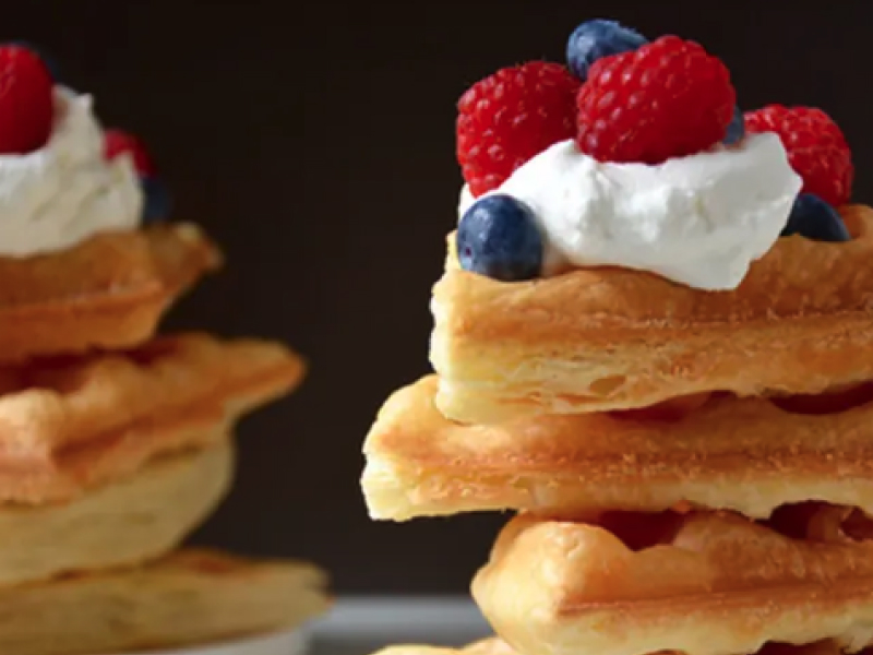 A mound of puff pastry waffles with whipped cream