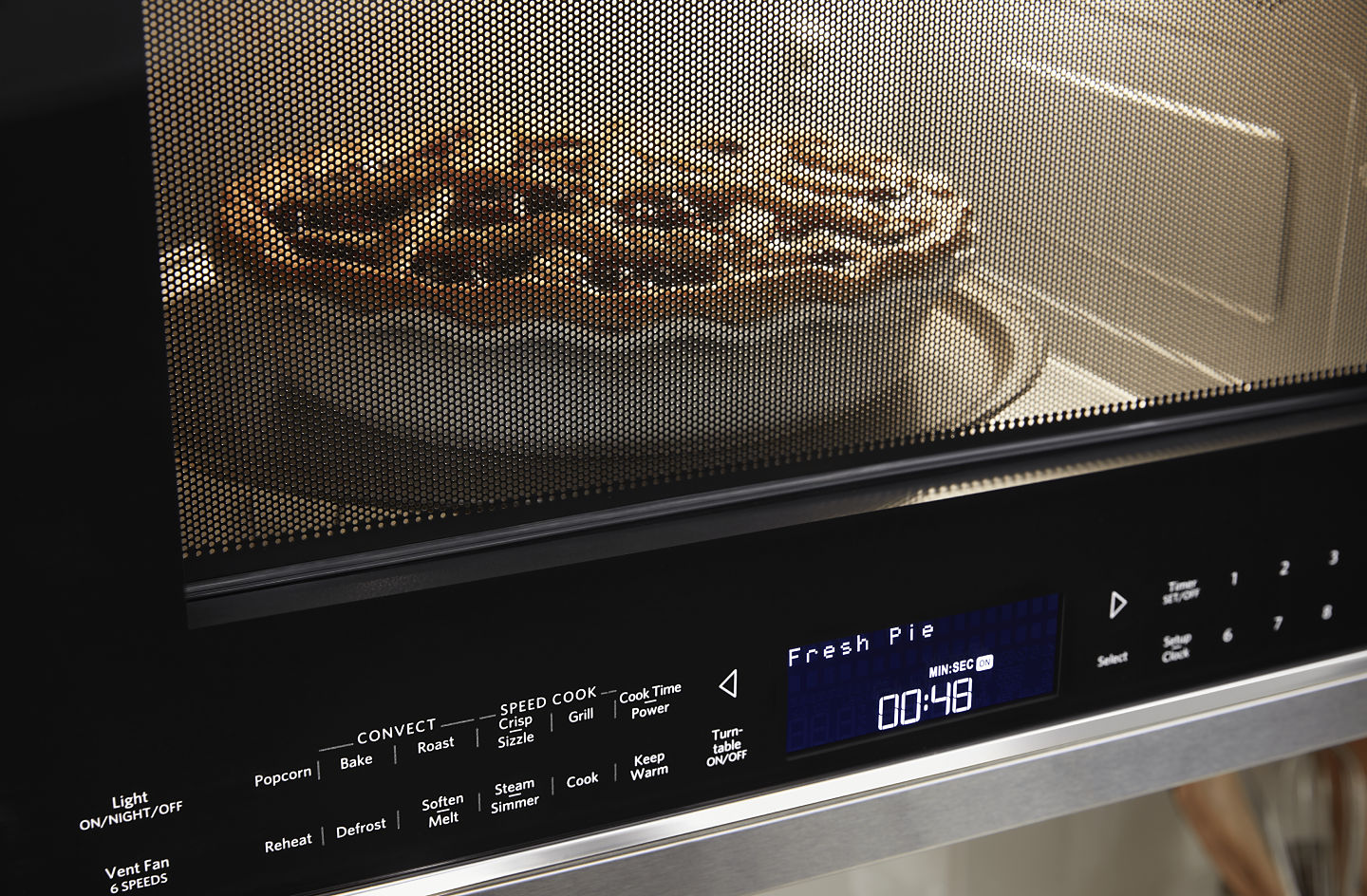 A closeup of a KitchenAid® microwave baking a pie.