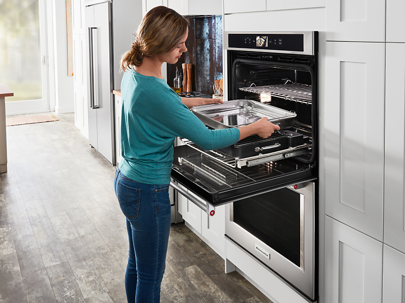 Woman removing baking sheet from the oven