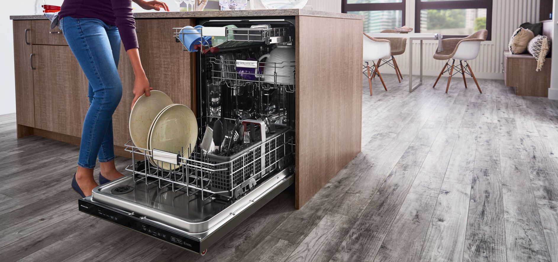Person loading plates into the bottom rack of a built-in dishwasher