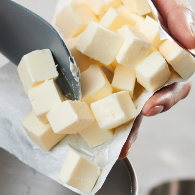 Person adding cubes of cold butter to stand mixer bowl