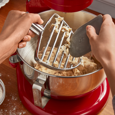 Person scraping dough off of pastry beater into stand mixer