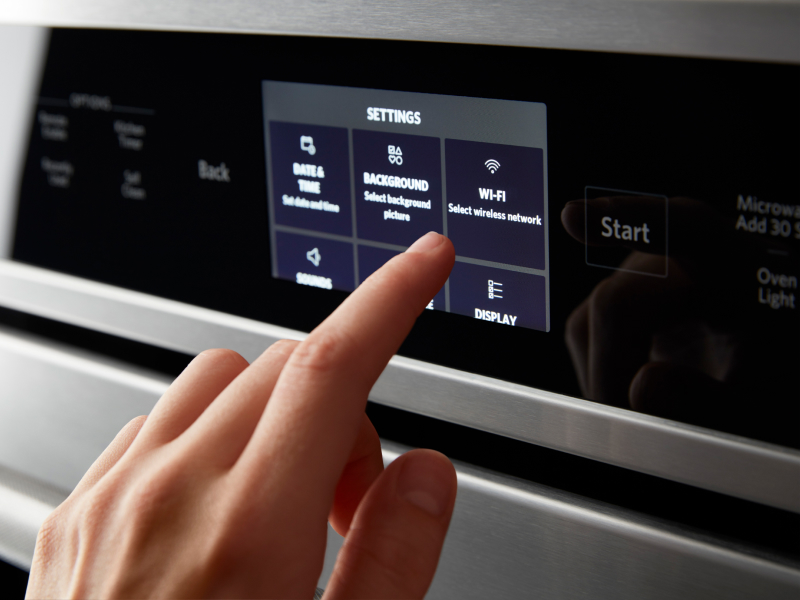 A person making a selection on the control pad of a smart oven
