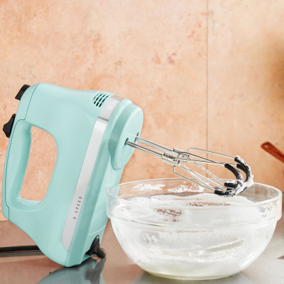 A corded hand mixer next to a bowl of icing