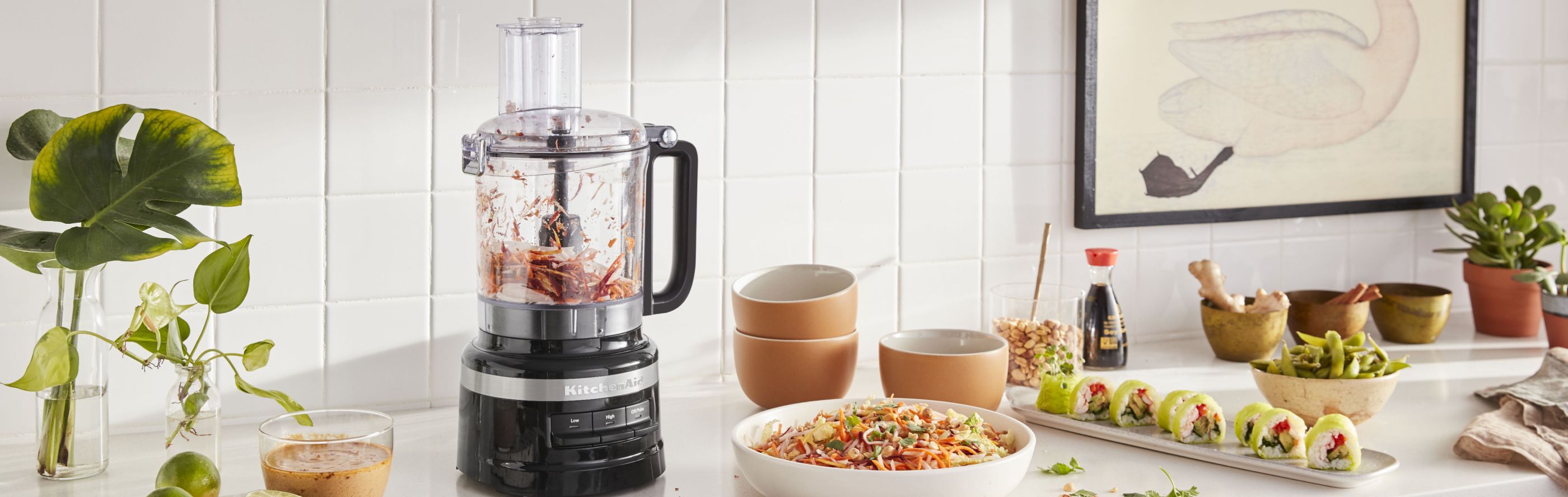 KitchenAid® food processor on countertop with sushi and cole slaw