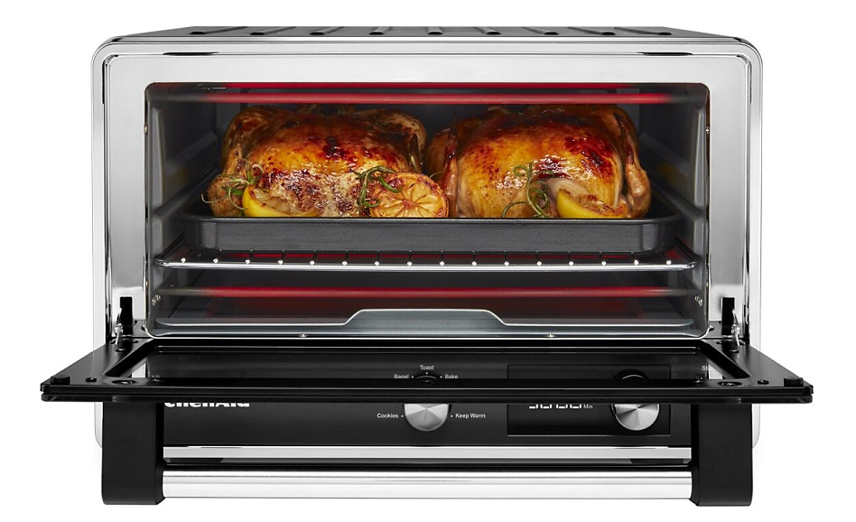 Open countertop oven with two roasted chickens inside