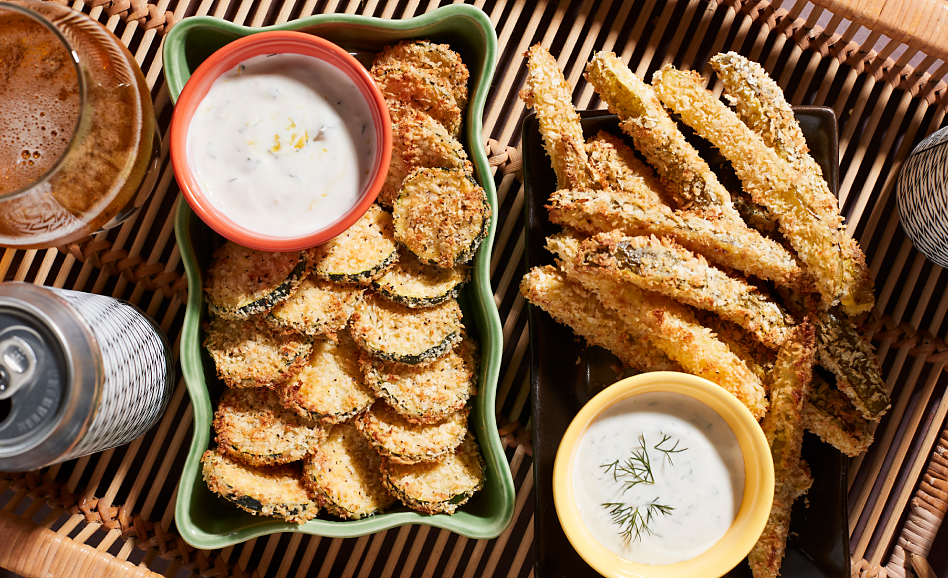 Breaded zucchini chips in platters with a creamy dip on the side and a can of soda
