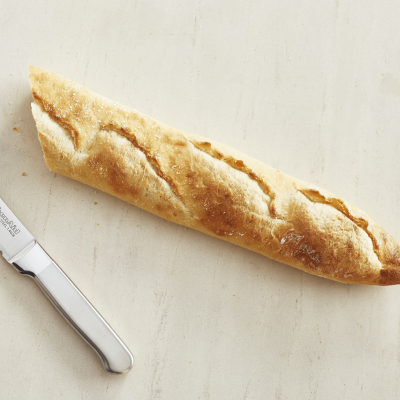 Fresh baguette next to a kitchen knife